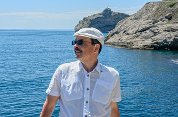 Mature man is posing on sea and cliffs background, Crimea.