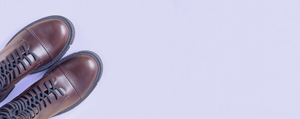 Brown shoes. Trendy Boots Pair on violet Background. Copy space, top view, flat lay. Shoe sale, fashion concept. Stylish Casual shoes for city. Overhead shot of chelsea boots. Urban lifestyle