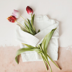 creative trendy flatlay with knitted sweater and fresh tulips, top view.