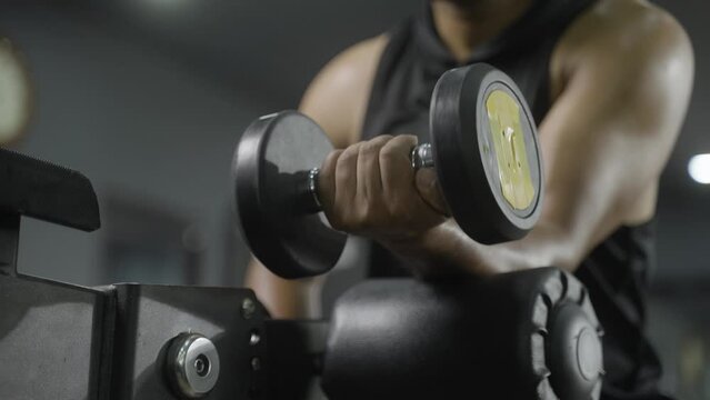Close up shot of man soing forearms workout using dumbbells at gym - cocept of fitness training, bodybuilding and healthy lifestyle.