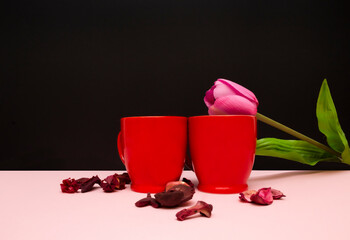 Coffee red cups on black background with pink rose. Coffee and love concept.