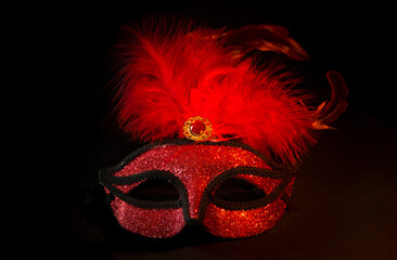 carnival symbol mask in red gold color with feathers on black background