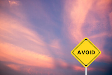 Yellow transportation sign with word avoid on violet color sky background