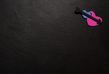 Blue and pink hearts with black arrow on black stone plate. Love valentine concept. Flat lay