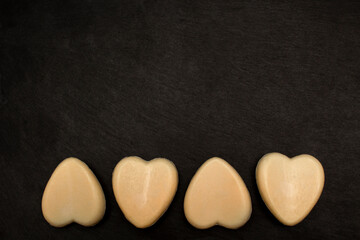 Four heart-shaped soaps on black background. Love valentine concept. Flat lay