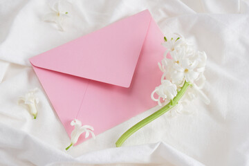 white hyacinth and pink envelope on white bed linen