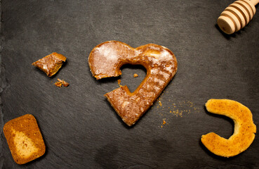 A piece of cookies, spoon for honey and heart shape cookie on black stone plate. Love valentine concept. Flat lay