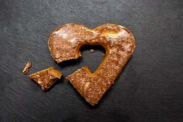 A piece of cookie cut and heart shape cookie on black stone plate. Love valentine concept. Flat lay