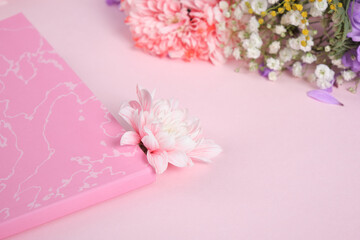 pink chrysanthemum bud in a pink notebook on a pink background, a bouquet of spring flowers, a romantic mood