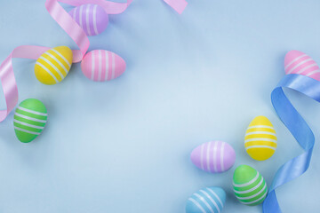 Top view of Easter eggs in pastel colors on light blue background with highlighted center. Flat lay image