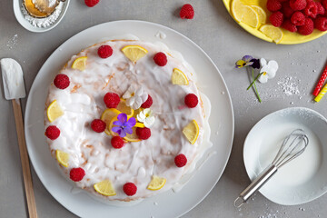 Selbstgemachter Zitronenkuchen dekoriert mit Zuckerguss, Himbeeren, Zitrone, Veilchen und Zutaten