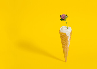 Ice cream cone with a purple flower. Minimal summer concept on yellow background.