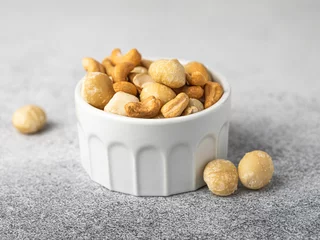 Foto op Aluminium Macadamia cashew nut food photo in a ceramic bowl. Healthy vegan nutrition snack with vitamins, oil. Food photo horizontal banner © Alina Nikitaeva