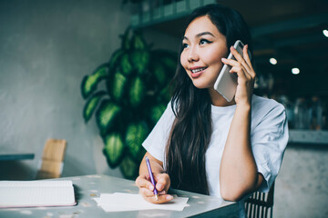 Cheerful woman talking on phone in cafe
