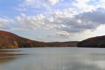 landscape lake in the mountains against a background of white clouds in a blue sky