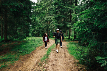 Stylish young people walking on trails in a mountain forest and making video content on a hike. Friends walk in nature on a trip in the mountains.