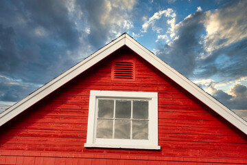 Peak of a rustic red building against a stormy sky.