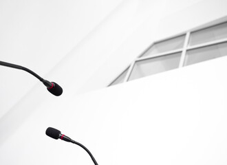 Press conference micro mics with a window of a modern white building in the background. 