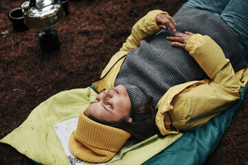Woman lying on sleeping bag while camping