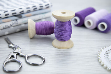 A spool of purple thread on a wooden table. Sewing accessories. Hobbies and recreation,sewing workshop.Trendy color, very peri