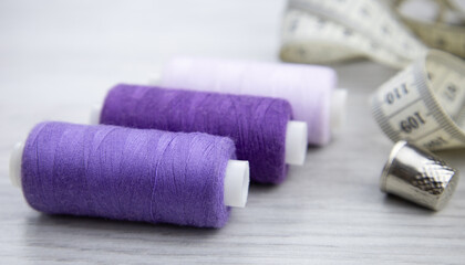 A spool of purple thread on a wooden table. Sewing accessories. Hobbies and recreation,sewing workshop.Trendy color, very peri