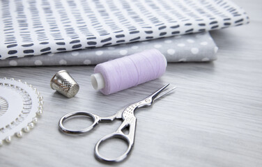 A spool of thread, scissors and cotton fabrics on the table.Sewing accessories.Hobbies and sewing