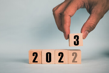 Hand hold wooden cubes 2023 and 2023 concept business change to new success