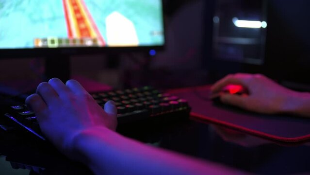 Professional gamer play computer video game in dark room, use neon colored rgb mechanical keyboard, place for cybersport gaming