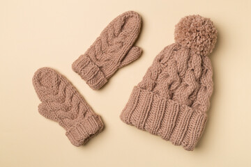 Brown winter hat and mittens on color background. Top view