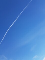 Fototapeta na wymiar White trail of an airplane in the blue sky