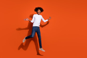 Photo of pretty impressed guy dressed white shirt running fast jumping high empty space isolated orange color background