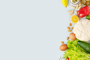 Food banner with organic vegetables and fruits, olive oil, nuts, seeds and eggs on a blue background with copy space. Concept of healthy food and diet. Foods with a lot of vitamins and nutrients