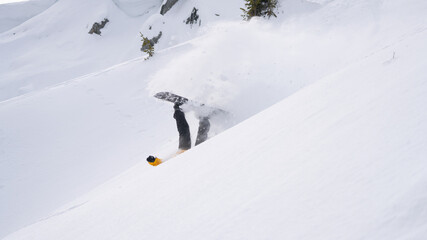 Snowboarder falls on a snow-covered off-piste slope.
