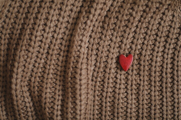 Decorative red heart on beige knitted sweater. Valentines day celebration or love concept.