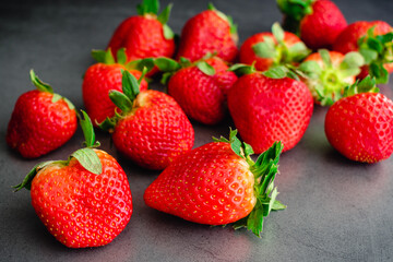 Fresh Whole Strawberries on a Dark Background: Grouping of ripe red berries on a dark stone countertop