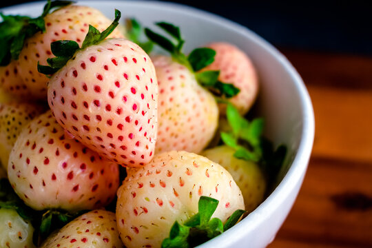 Fresh White Pineberries with Water Drops: Closeup of whole wet white strawberries in a ceramic bowl