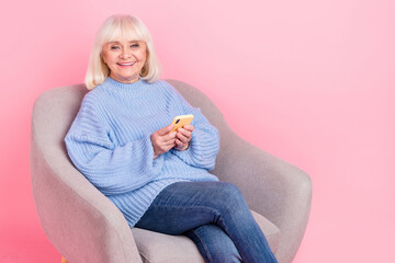 Fototapeta premium Portrait of attractive cheery grey-haired woman using gadget device blogging post app isolated over pink pastel color background