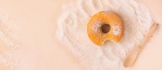 doughnut bitten on apricot colour background with sugar and wooden teaspoon. Copy space