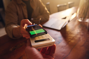 Hand using mobile payment to pay for coffee in coffee shop