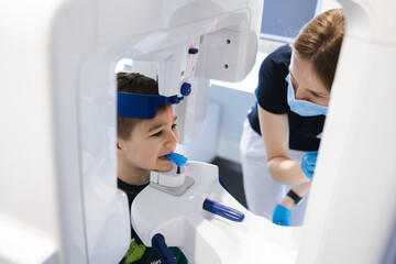 Radiographer taking panoramic teeth radiography to a little boy using modern x-ray machine