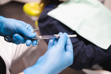 Close-up of a male dentist holding a syringe with painkillers in his hands