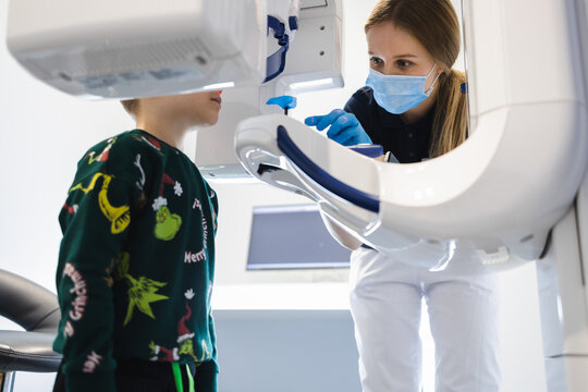 Radiographer taking panoramic teeth radiography to a little boy using modern x-ray machine