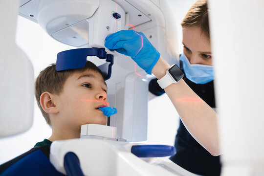 Dentist taking panoramic teeth radiography to a little boy using modern x-ray machine
