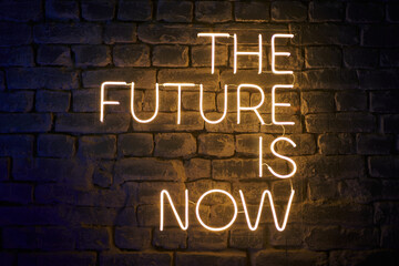neon glowing inscription on the wall the future is now - obrazy, fototapety, plakaty