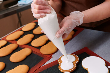 applying a layer of glaze to a confectionery product using a pastry bag. A row of gingerbread...