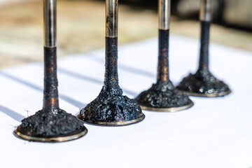 Engine valves in oil covered with soot. Heat-resistant steel. Automotive, repair servicing.