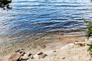 stones on the shore of a lake overgrown with forest