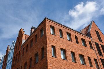 Red brick wall with windows against blue sky