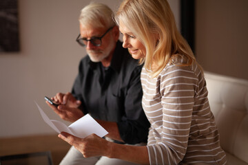 A married couple calculates expenses. Husband and wife do paperwork. Invoices for payment,...