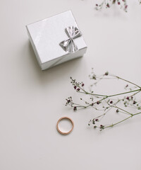 Box with golden engagement ring on flowers background, top view. Wedding, Marriage proposal concept